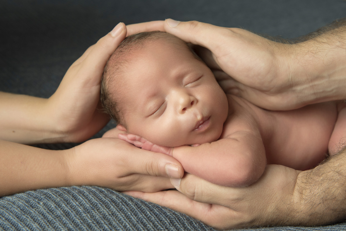 Un neonato tenuto tra le mani dei genitori